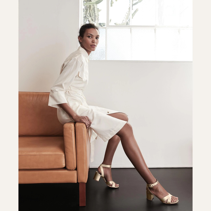 model wearing the gold version of the sandals