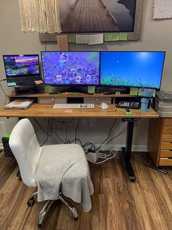 a workspace with a desk, ergonomic chair, and two monitors plus a laptop