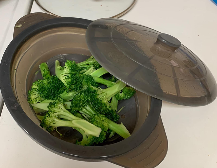 A reviewer's photo of the steamer bowl with its lid removed, showcasing freshly steamed broccoli.