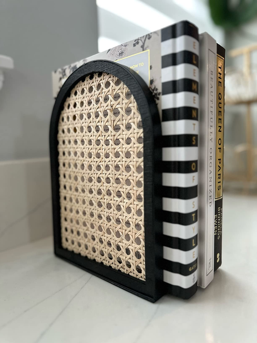 A black and rattan bookend supporting a reviewer’s books.