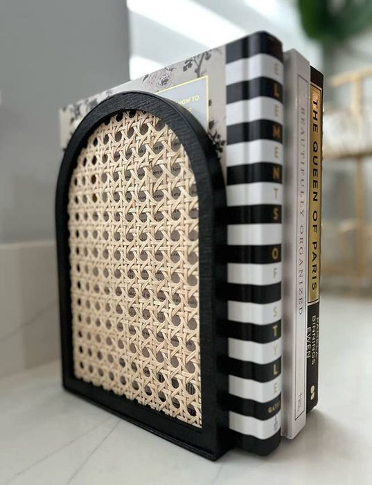 A black and rattan bookend supporting a reviewer’s books.