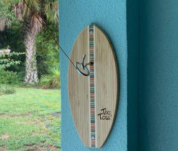 A reviewer's photo showing the Tiki Toss game mounted on an outdoor wall