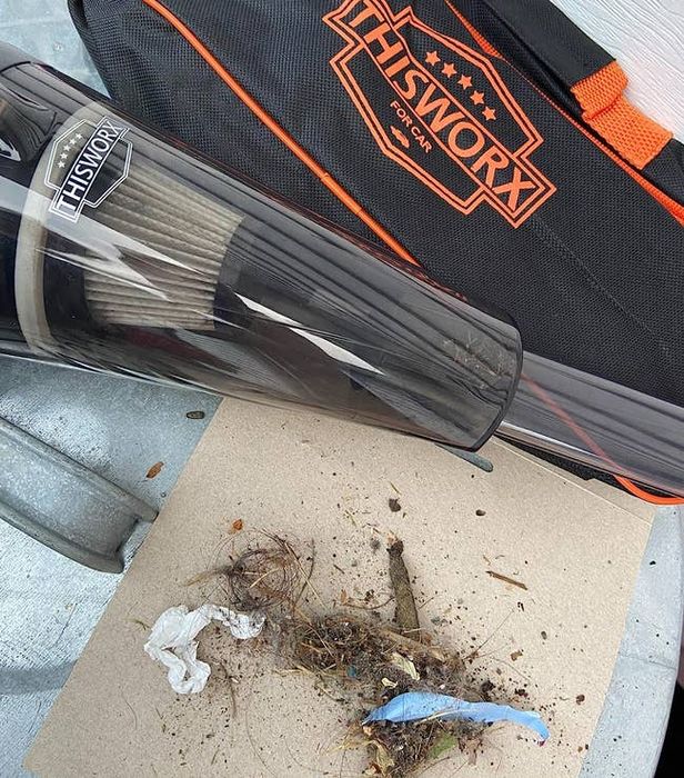 A reviewer’s vacuum next to a pile of twigs and dirt it has collected