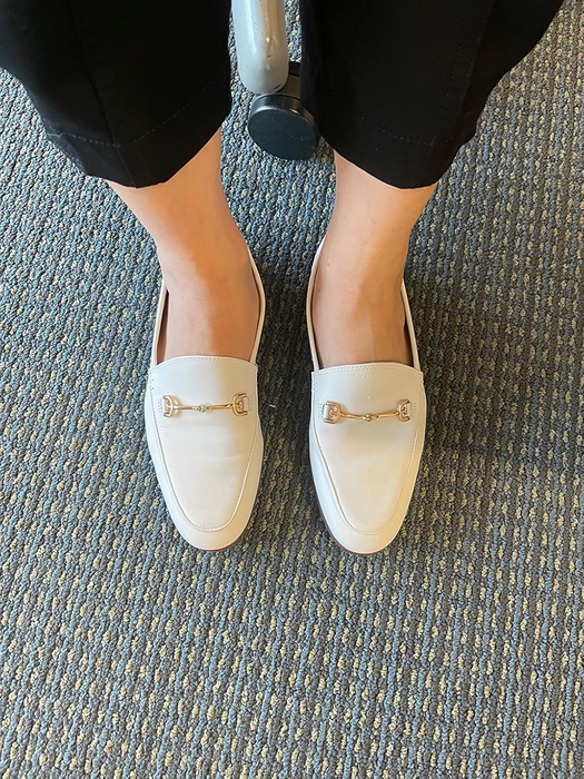 reviewer showcasing white loafers