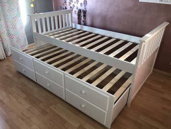 A reviewer's photo showing a white frame bed with convenient storage drawers underneath.