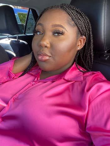 A reviewer models the satin button-up in pink.