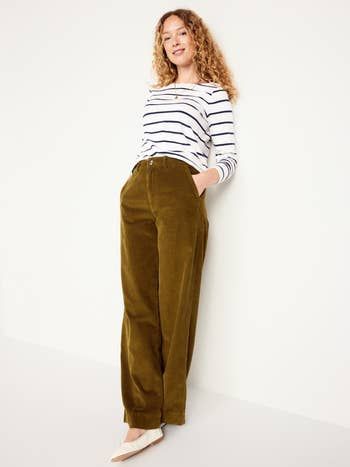 A person models a striped long-sleeve shirt paired with wide-leg pants, hands casually resting in pockets. Featured in a fashion article for shopping inspiration.