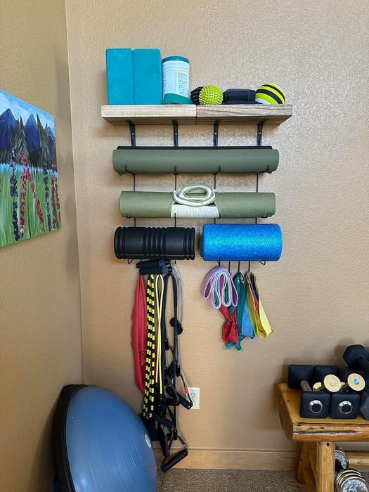 Home gym equipment arranged on wall shelves, including mats, resistance bands, foam rollers, weights, and a medicine ball.
