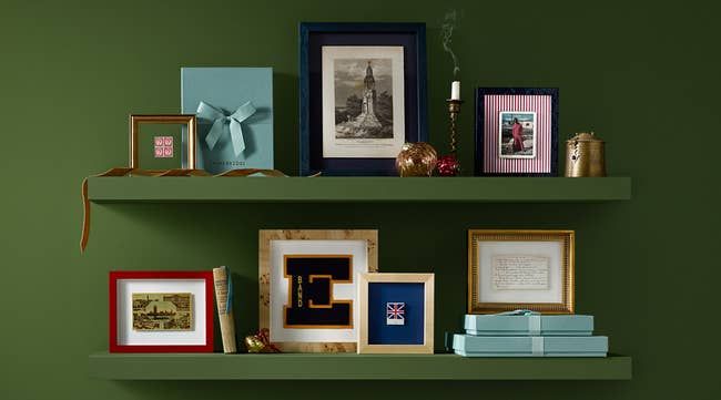 Two shelves showcasing framed art, books, a candle, and gift boxes, offering inspiration for gift or home decor ideas.