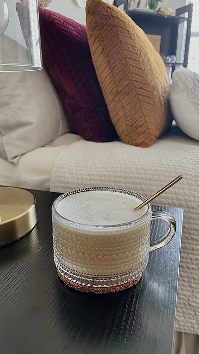 A glass mug with delicate line and dot patterns, filled with coffee.