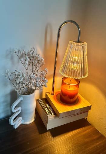 The candle warmer illuminated, with a candle beneath the bulb melting