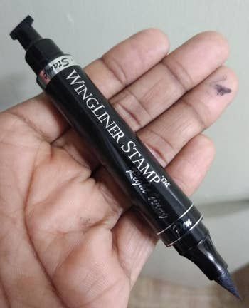 a user holding the eyeliner pen/stamp in hand