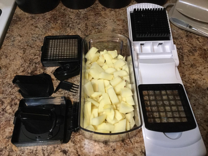 A reviewer's photo showcasing the chopper, its attachable blades, and a container filled with neatly chopped potatoes.