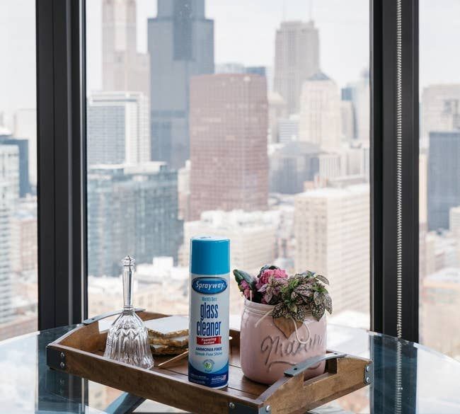 The can of Sprayway glass cleaner resting on a glass table next to a large window.