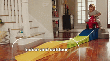 A GIF of a child model riding a red scooter down a colorful ramp.