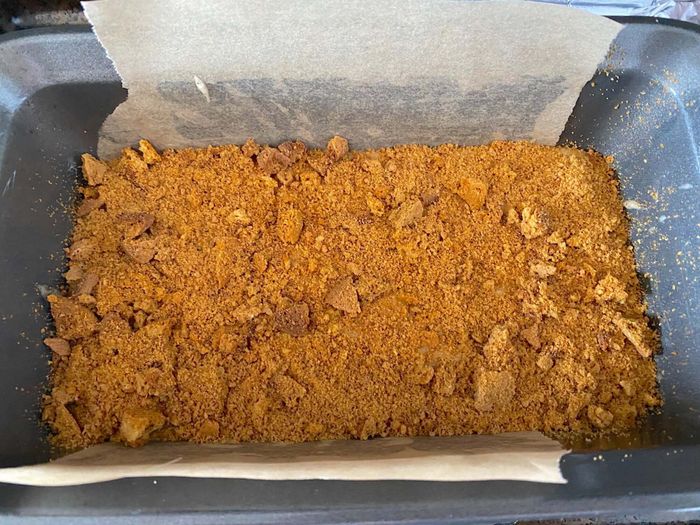 The finished cake in the loaf pan, topped with a mix of large and small cookie crumbles.