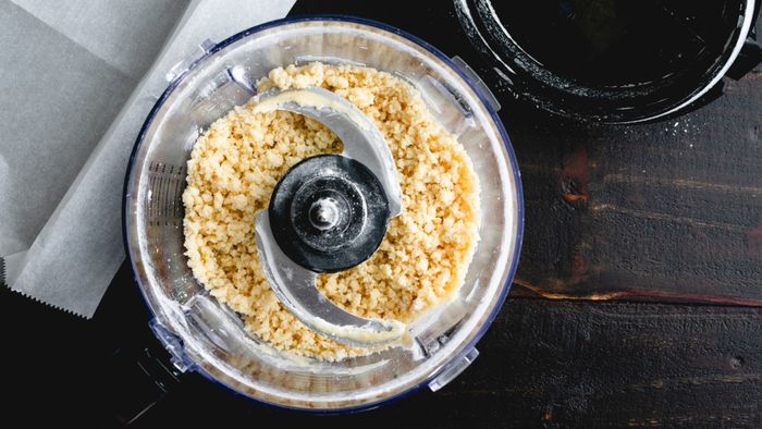 A food processor containing crumbly dough.