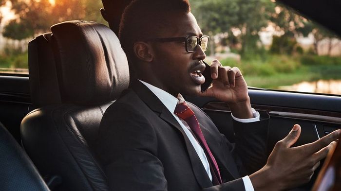 A focused young businessman engaged in a conversation on his cell phone while sitting in the driver's seat