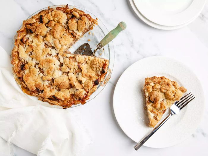 Overhead view of an apple pie baked in a brown paper bag, with a slice displayed beside it