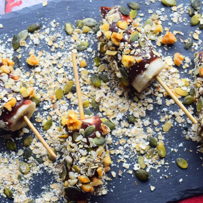 Bananas on skewers coated in frozen chocolate and sprinkled with nuts