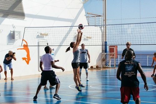 a group of people enjoying a game of volleyball at the sports square on a Dinogo ship