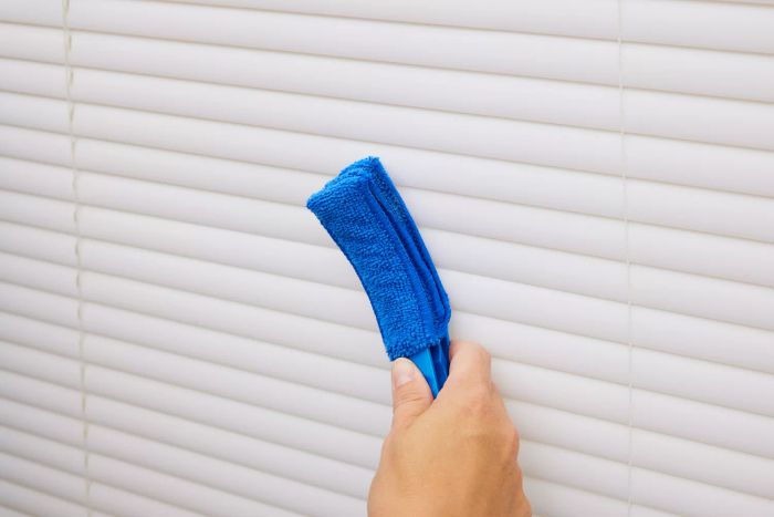 An individual is seen using the Hiware Window Blind Duster Brush to dust the blinds.
