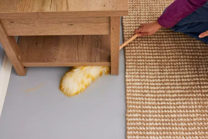 A person uses the Green Vivid Lambswool Duster to remove dust.
