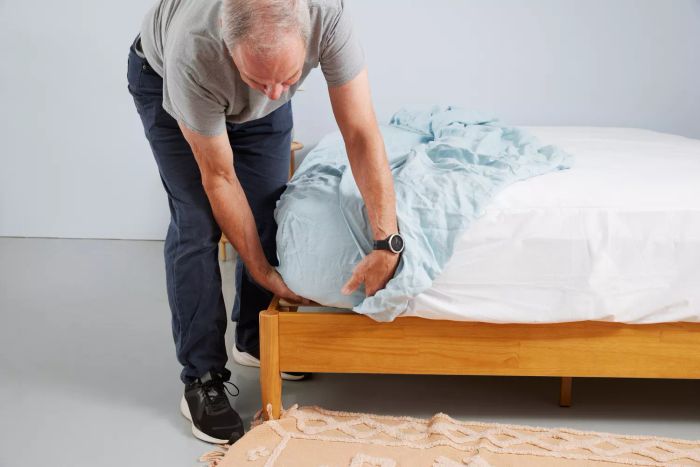 A person places the Tuft & Needle Hemp Sheet Set on the bed