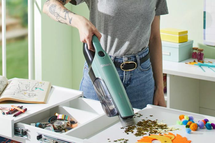 A person cleaning a messy table with the Shark UltraCyclone Pro Cordless Handheld CH901