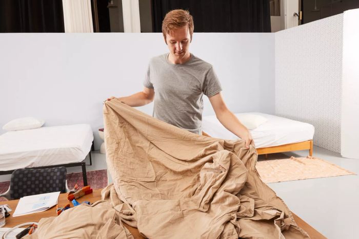 A person inspects the Lands' End 120 Thread Count Garment Washed Cotton Hemp Blend Bed Sheet Set, spread out on a table.