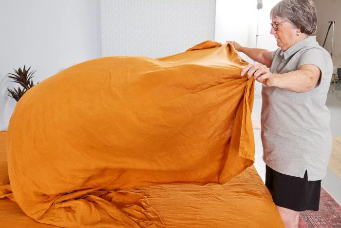 A person making the bed with the Everly Hemp Sheet Set