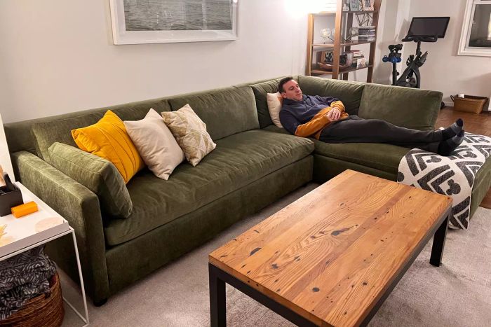 An individual relaxing on the West Elm Marin 2-Piece Bumper Chaise Sectional