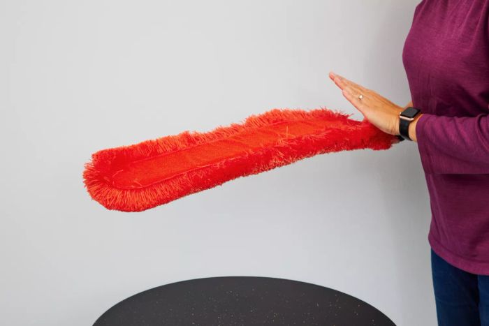 An individual interacts with the OXO Good Grips Under-Appliance Microfiber Duster.