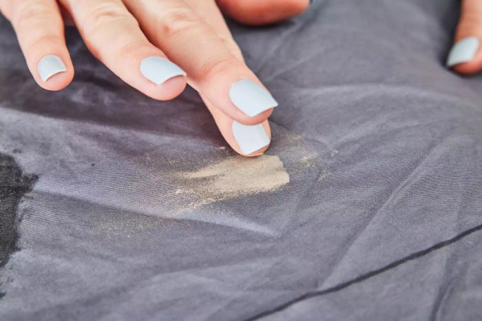 A hand adding a stain to the Sijo Home Organic Percale Cotton CrispCool Sheet Set