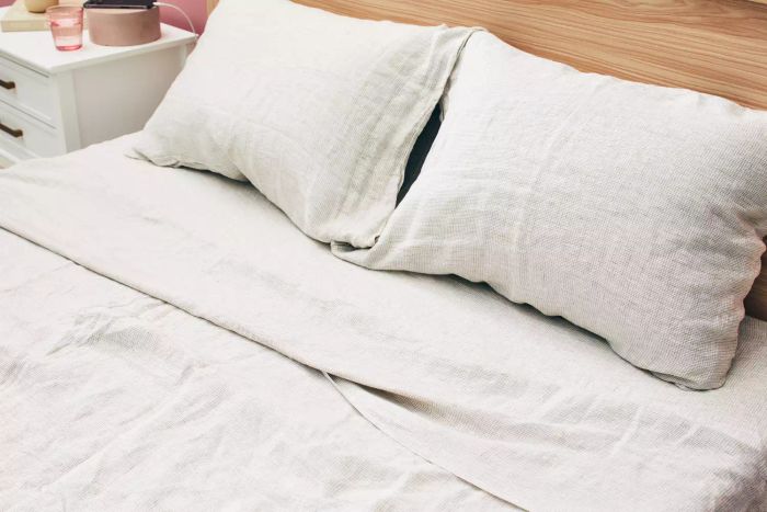 A bed arranged with the Crate & Barrel Garden Green Grid Natural Hemp Fiber Queen Bed Sheet Set.