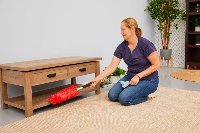 A person is dusting a table using the OXO Good Grips Microfiber Hand Duster.
