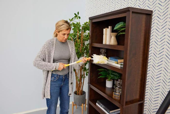 A person is using the Swiffer 360 Duster on a bookshelf.