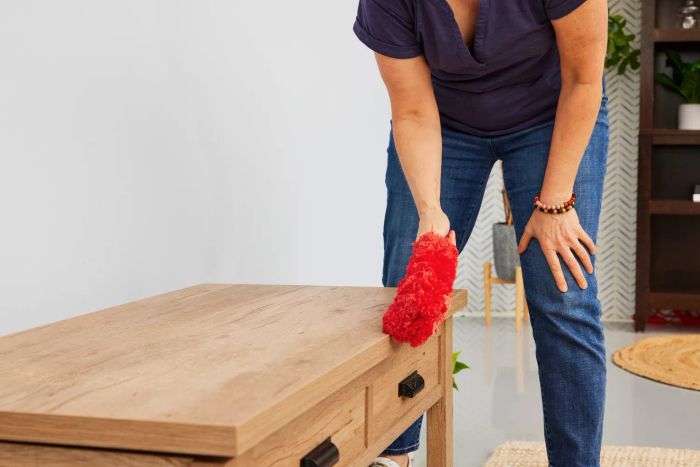 A person is dusting a table with the OXO Good Grips Microfiber Hand Duster.
