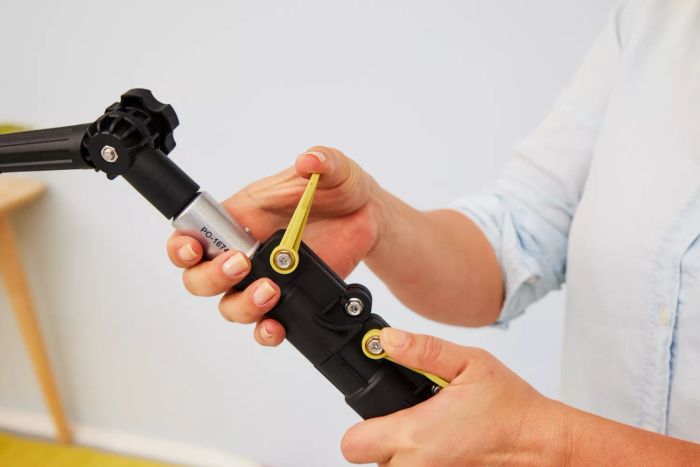 A person is making adjustments to the DocaPole Microfiber Duster with Extension Pole.