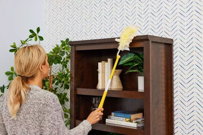 A person is dusting with the Swiffer 360 Heavy Duty Duster with Extendable Handle Starter Kit.