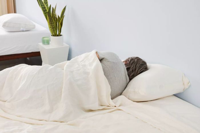 A person relaxing in a bed adorned with Avocado Organic Hemp Sheets.
