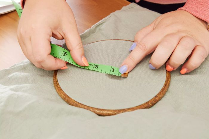 A person measuring a section of the Casaluna 100% Washed Hemp Solid Sheet Set with a tape measure.