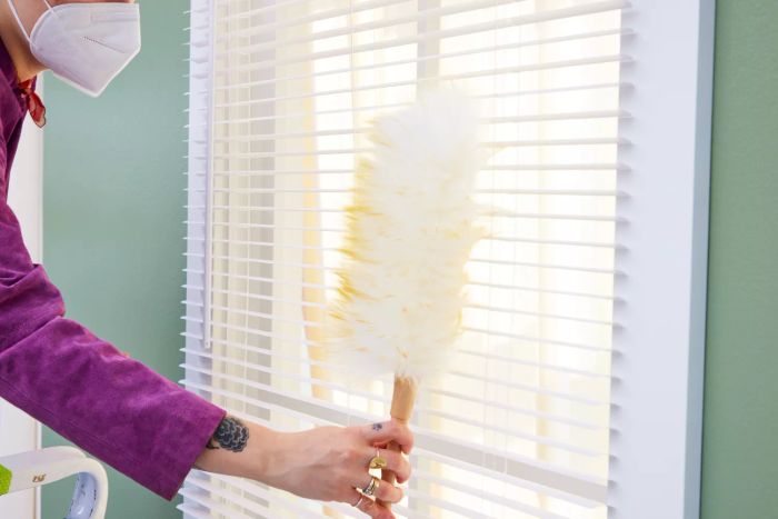 A person uses the Green Vivid Lambswool Duster to clean the blinds.