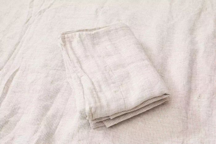 A Crate & Barrel Garden Green Grid Natural Hemp Fiber Queen Bed Sheet Set neatly folded.