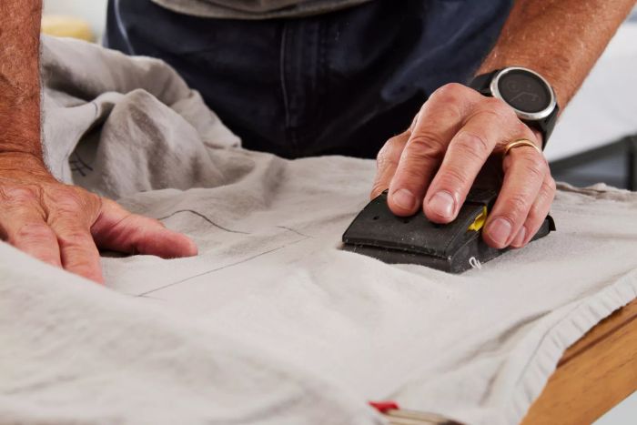Hands use a sanding tool on the Delilah Home Hemp Sheet Set.