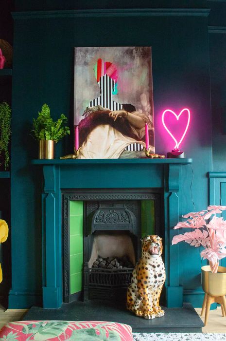 A pink neon heart light placed above a teal fireplace mantel.