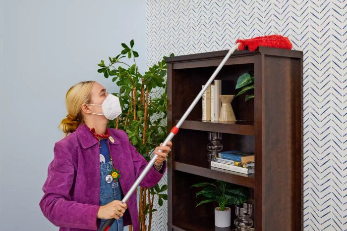 An individual uses the OXO Good Grips Microfiber Extendable Duster to dust.