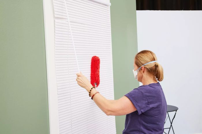 A person is dusting blinds with the OXO Good Grips Microfiber Hand Duster.