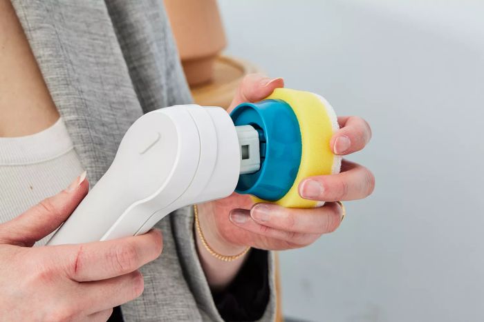 A person detaches the sponge from a Black+Decker Grimebuster Pro Power Scrubber Brush