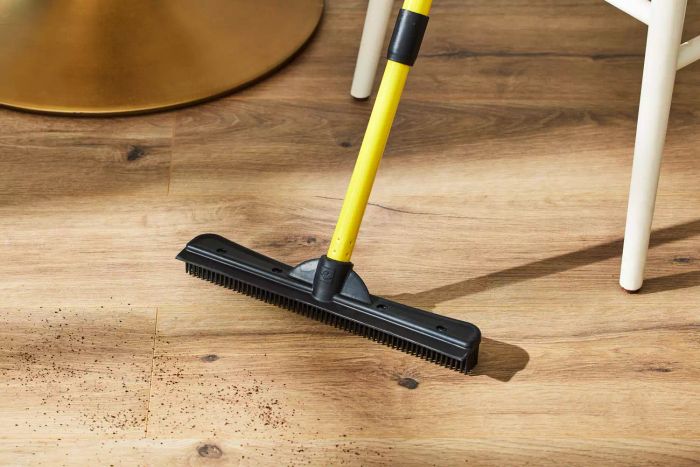 The FURemover Pet Hair Rubber Broom in action on a wooden floor